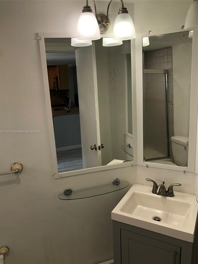 bathroom featuring vanity, toilet, and an enclosed shower