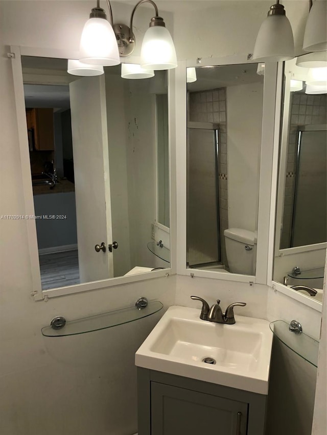 bathroom featuring vanity, toilet, and a shower with shower door