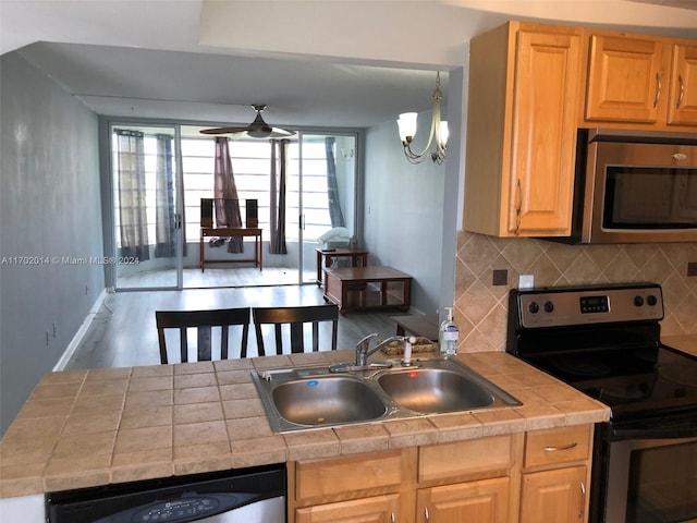 kitchen with ceiling fan with notable chandelier, sink, decorative backsplash, light wood-type flooring, and appliances with stainless steel finishes