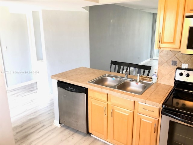 18900 NE 14th Ave Unit D204, Miami, FL 33179 - kitchen with appliances with stainless steel finishes, light brown cabinets, tile countertops, light wood-style flooring, and backsplash