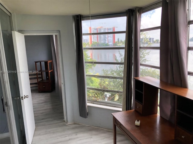 interior space with a wealth of natural light, a water view, and light wood-type flooring