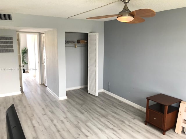 unfurnished bedroom featuring ceiling fan, a closet, a textured ceiling, and light hardwood / wood-style flooring