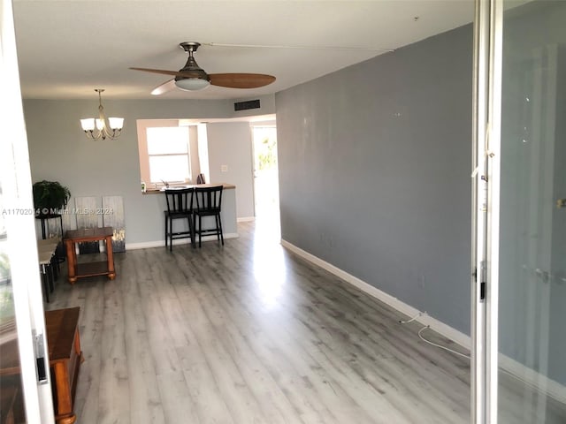 interior space featuring ceiling fan with notable chandelier and hardwood / wood-style flooring