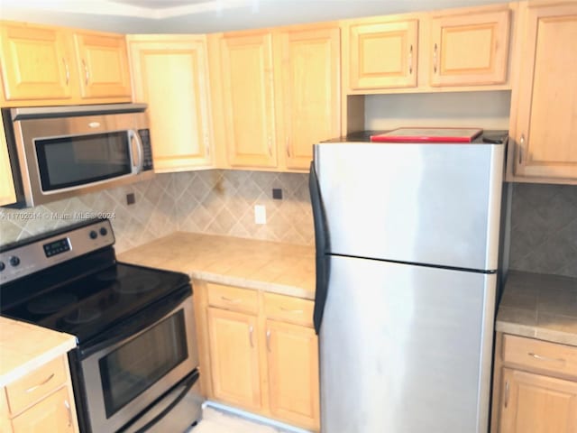 kitchen with light brown cabinets, backsplash, and appliances with stainless steel finishes