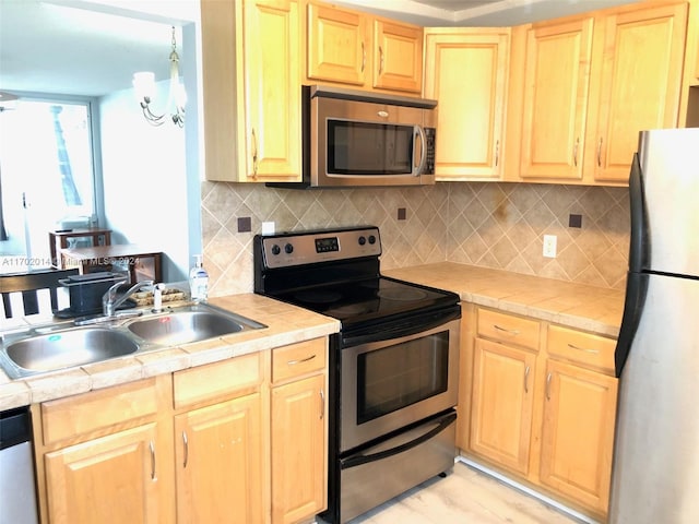 kitchen with decorative backsplash, sink, stainless steel appliances, and an inviting chandelier