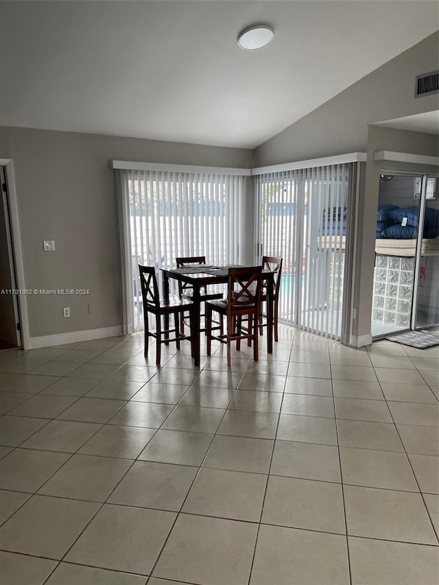 dining area featuring light tile patterned flooring, a wealth of natural light, and vaulted ceiling