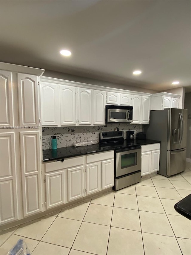 kitchen featuring backsplash, white cabinetry, stainless steel appliances, and light tile patterned floors