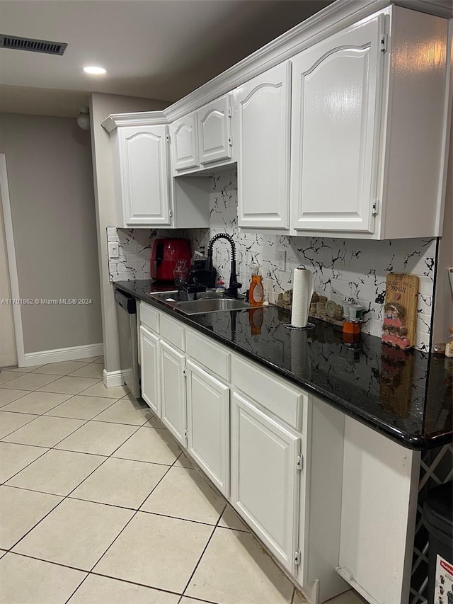 kitchen featuring dark stone counters, sink, dishwasher, white cabinets, and light tile patterned flooring