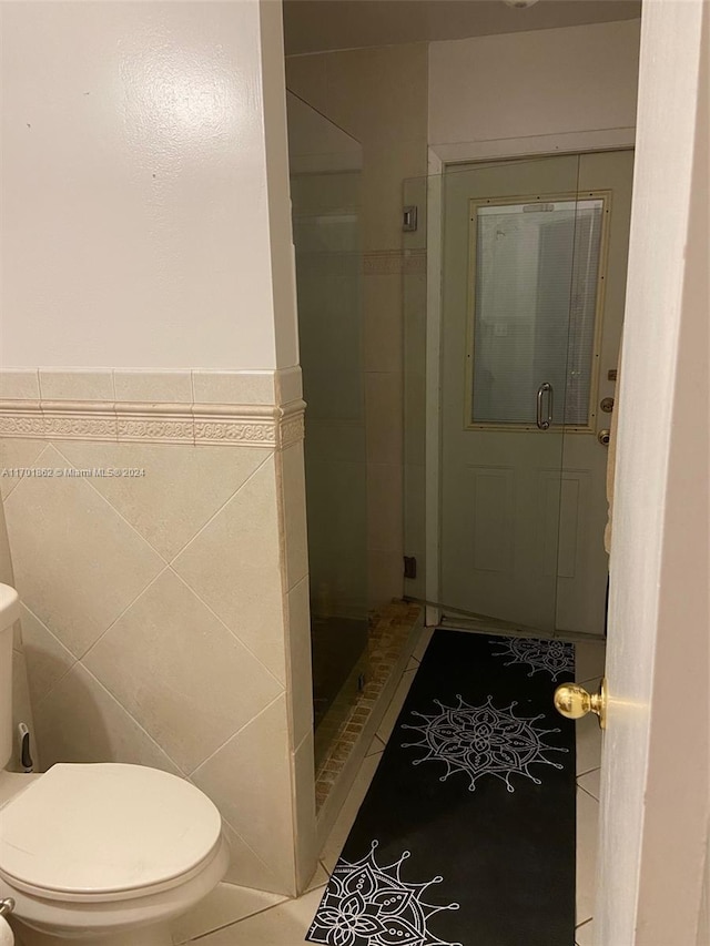 bathroom with tiled shower, toilet, and tile walls