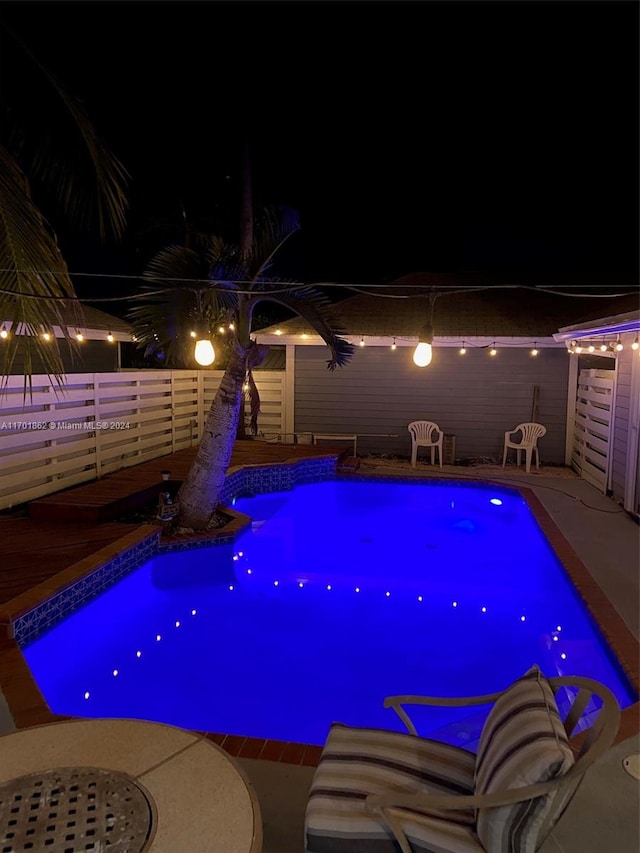 pool at twilight with a patio area