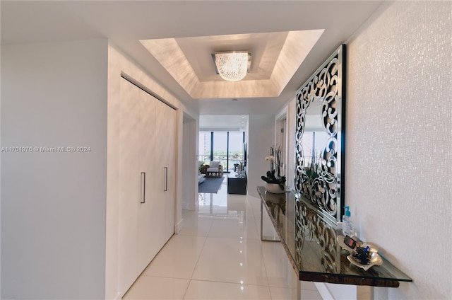 hall featuring light tile patterned flooring and a raised ceiling