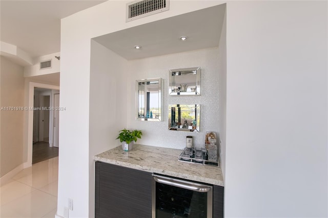 bar with wine cooler, light stone counters, and light tile patterned floors