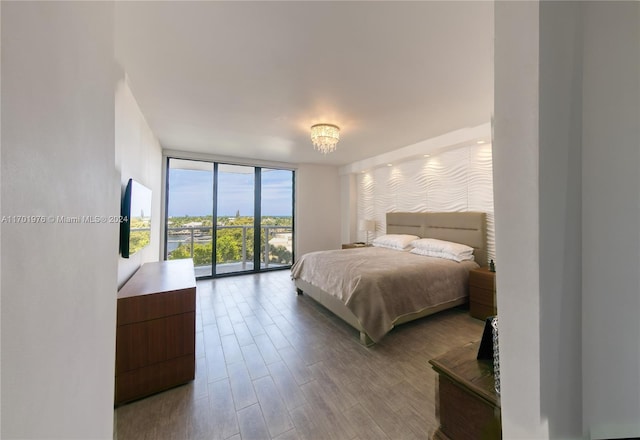 bedroom with expansive windows, light wood-type flooring, access to outside, and a chandelier