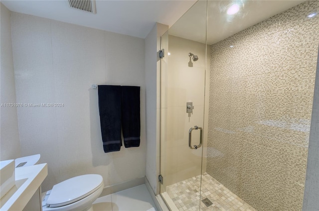 bathroom featuring tile patterned floors, vanity, toilet, and a shower with door