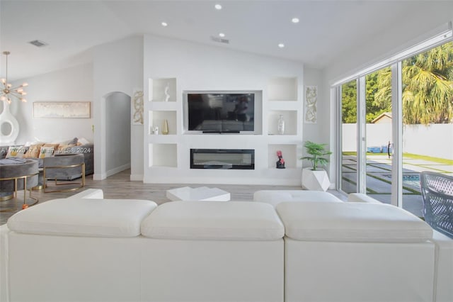 living room featuring built in shelves, a notable chandelier, lofted ceiling, and light wood-type flooring