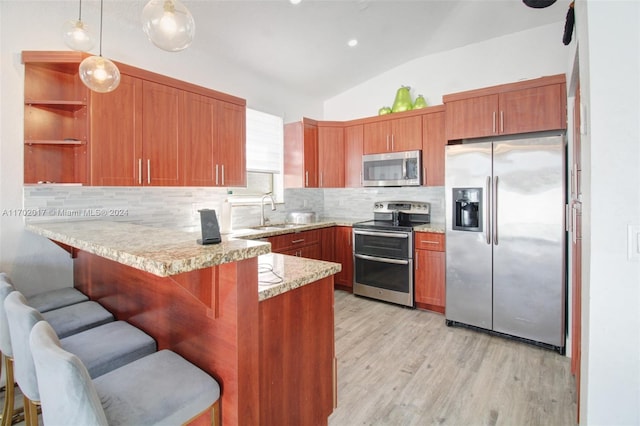 kitchen with lofted ceiling, hanging light fixtures, light hardwood / wood-style floors, kitchen peninsula, and stainless steel appliances