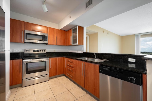 kitchen featuring light tile patterned flooring, dark stone countertops, sink, and appliances with stainless steel finishes