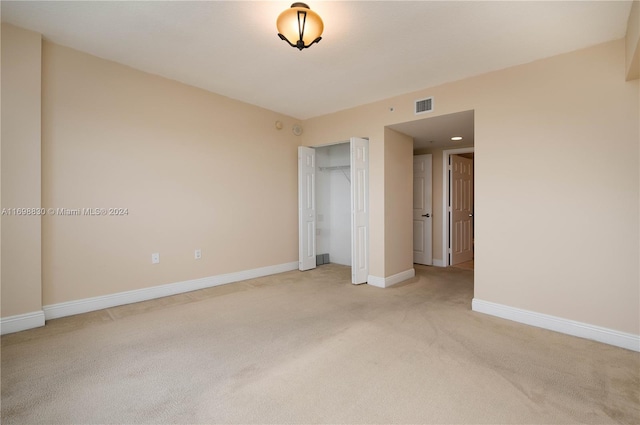 unfurnished bedroom with light carpet and a closet