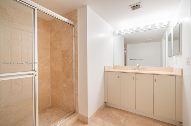 bathroom featuring tile patterned flooring, vanity, and a shower with door