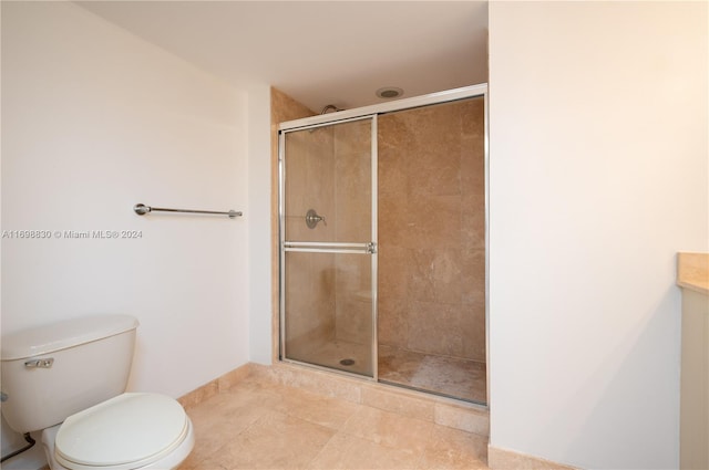 bathroom featuring tile patterned floors, a shower with door, vanity, and toilet