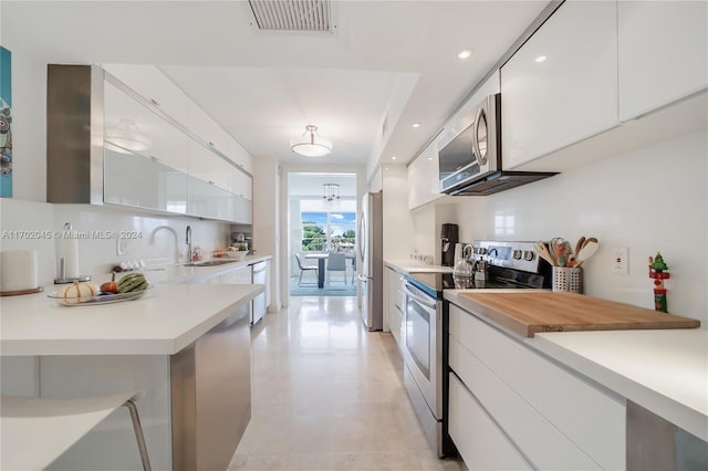 kitchen featuring white cabinets, sink, stainless steel appliances, and wooden counters