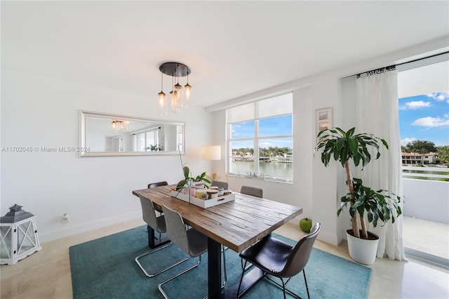 dining area featuring a water view and a notable chandelier