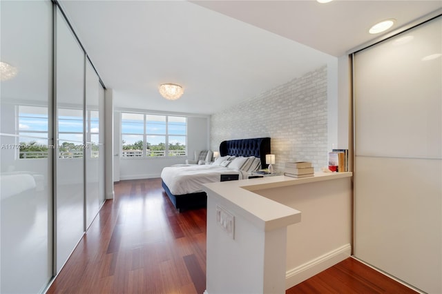 bedroom featuring dark hardwood / wood-style floors and brick wall