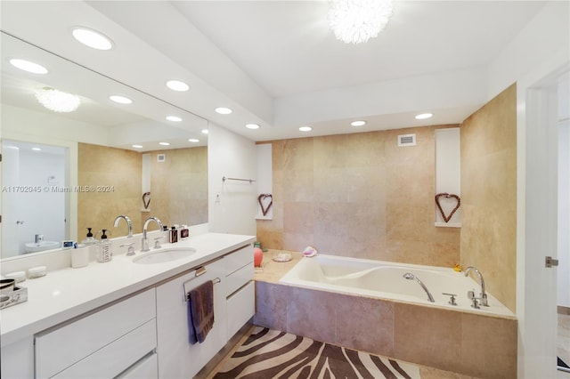 bathroom featuring tile patterned flooring, vanity, and tiled bath