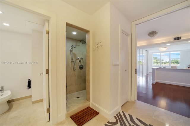 bathroom with hardwood / wood-style floors, tiled shower, and a bidet