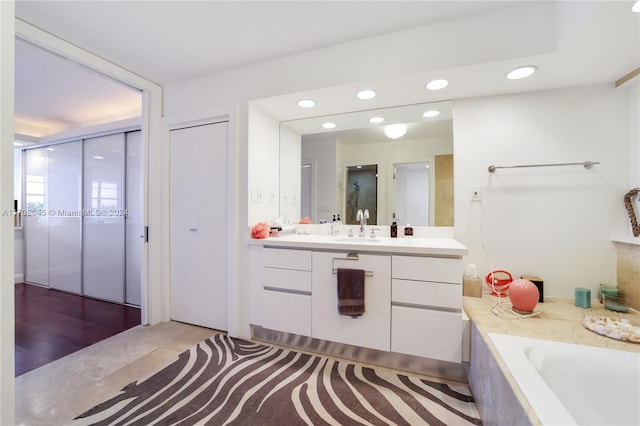 bathroom featuring hardwood / wood-style floors, vanity, and a washtub