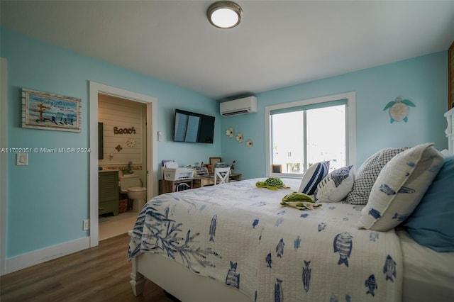 bedroom with ensuite bathroom, dark wood-type flooring, and a wall unit AC