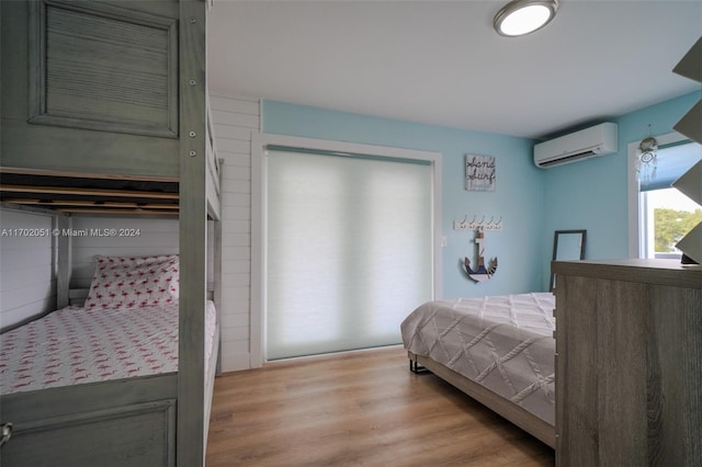 bedroom with a wall mounted air conditioner and light wood-type flooring