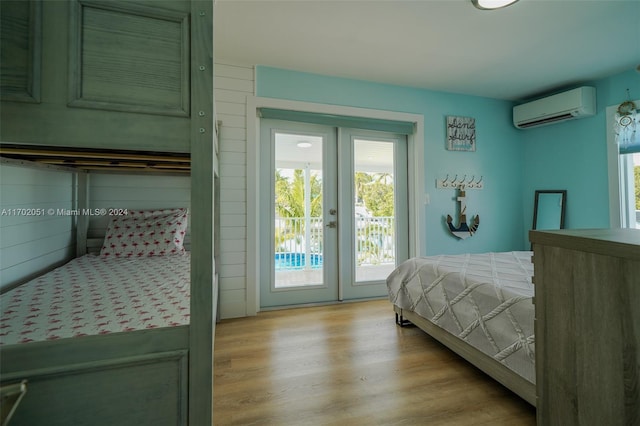 bedroom featuring access to outside, a wall mounted AC, and light hardwood / wood-style floors