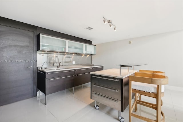 kitchen with a kitchen island, light tile patterned floors, sink, and tasteful backsplash