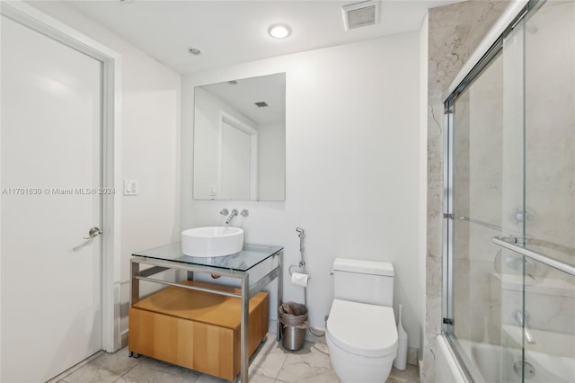 full bathroom with vanity, bath / shower combo with glass door, and toilet