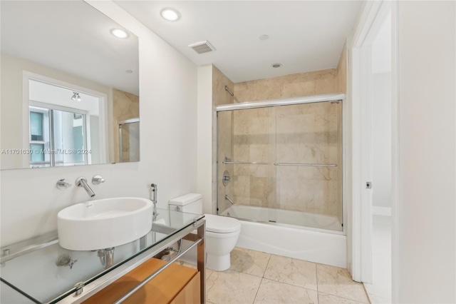 full bathroom featuring enclosed tub / shower combo, toilet, and sink