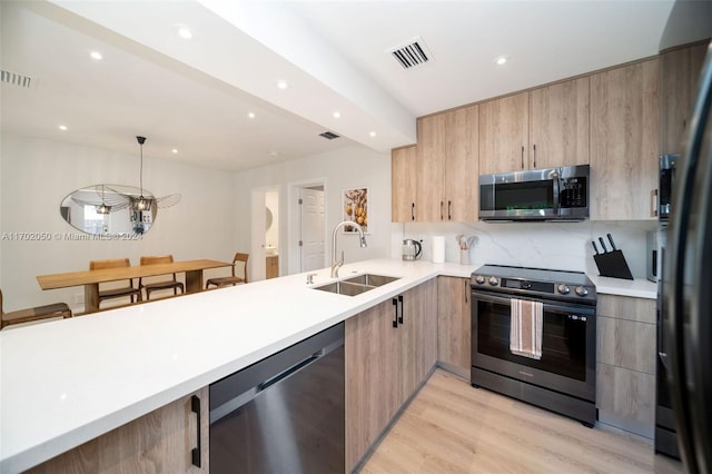 kitchen featuring sink, stainless steel appliances, tasteful backsplash, light hardwood / wood-style floors, and decorative light fixtures