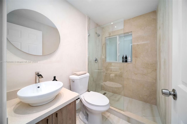 bathroom with a tile shower, vanity, and toilet