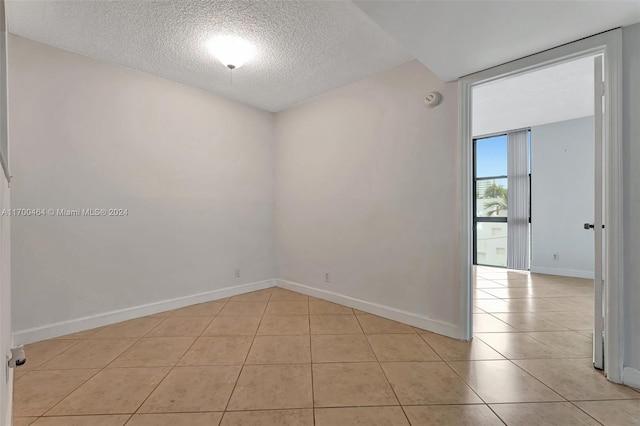 unfurnished room with a textured ceiling and light tile patterned flooring