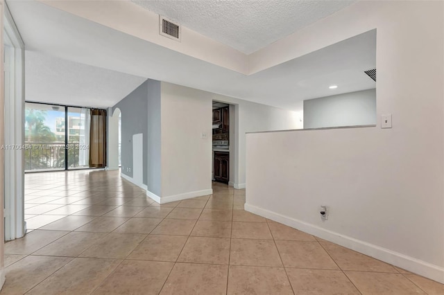 tiled empty room with a textured ceiling and floor to ceiling windows