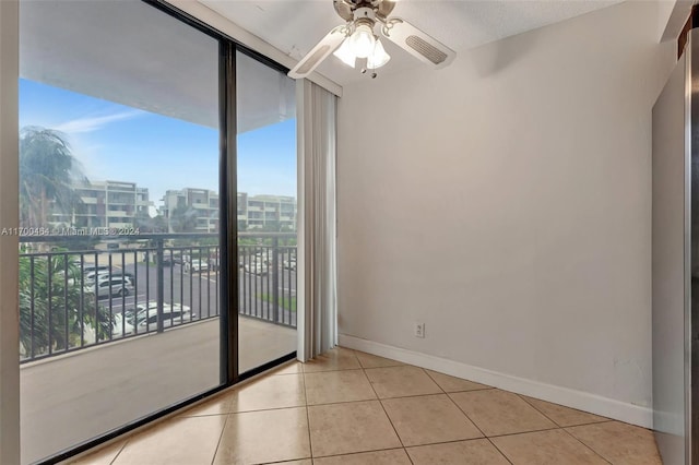 tiled empty room with plenty of natural light, ceiling fan, a textured ceiling, and expansive windows