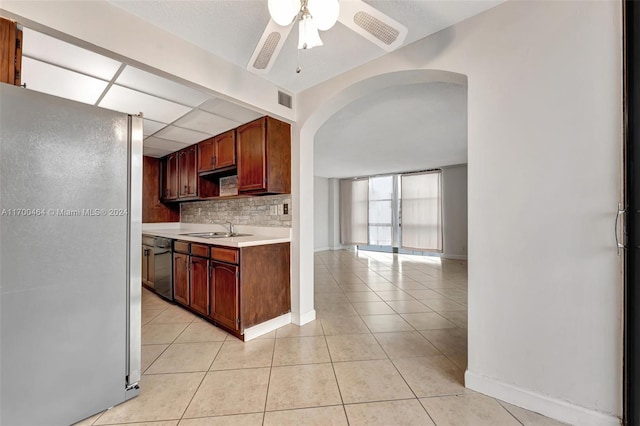 kitchen featuring sink, ceiling fan, stainless steel fridge, light tile patterned floors, and tasteful backsplash