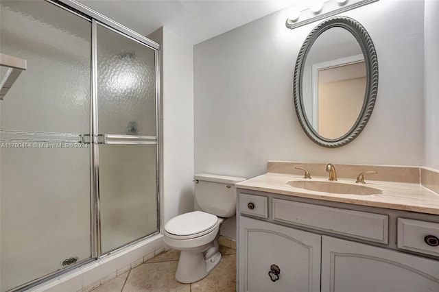 bathroom featuring tile patterned flooring, vanity, a shower with door, and toilet