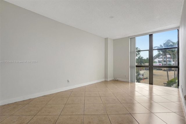 spare room with light tile patterned floors, a textured ceiling, and a wall of windows