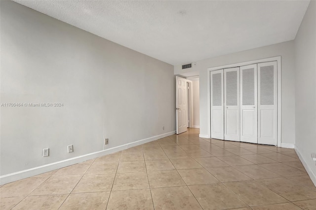 unfurnished bedroom with light tile patterned floors, a textured ceiling, and a closet