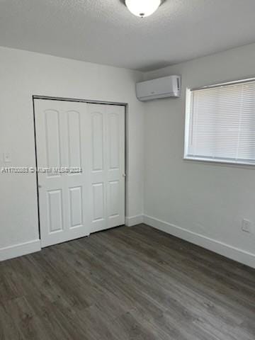 unfurnished bedroom featuring a closet, dark hardwood / wood-style floors, and a wall mounted AC