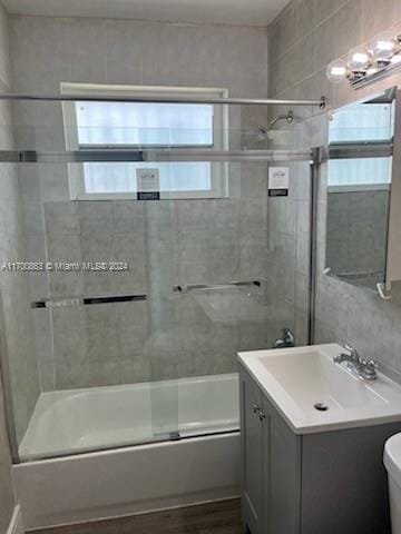 full bathroom featuring vanity, enclosed tub / shower combo, and toilet