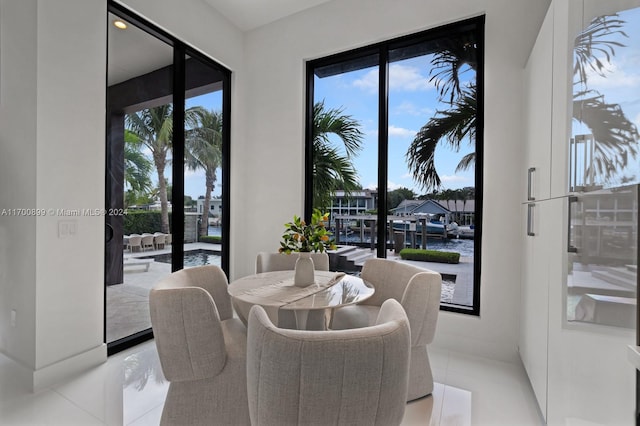 dining room with plenty of natural light, a water view, and light tile patterned floors