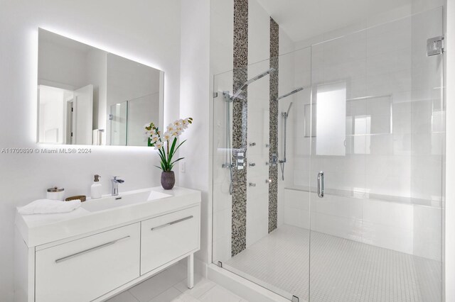 bathroom with tile patterned flooring, vanity, and walk in shower