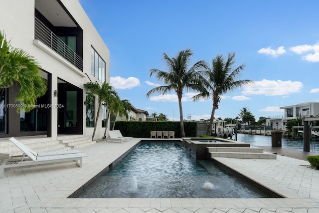 view of swimming pool featuring pool water feature, a patio area, a water view, and an in ground hot tub